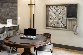A dining table with chairs and a Scrabble board on the wall.